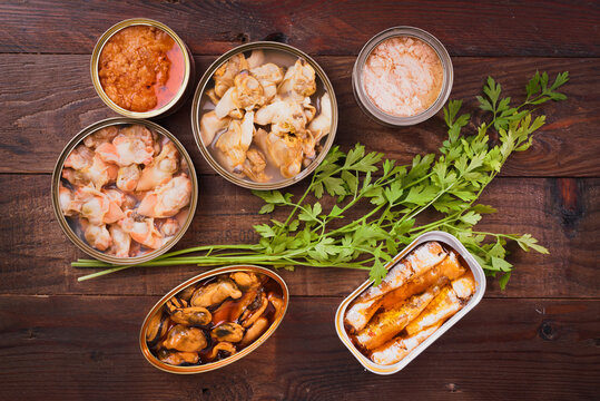 Top view of assorted canned seafood with herbs on table