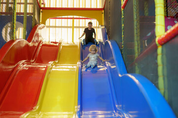 Children enjoying colorful slides in an indoor play area during the afternoon