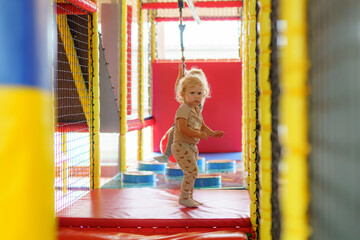 Child playing in an indoor play area with bright colors and climbing structures in the afternoon