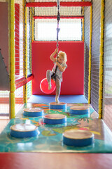 Child enjoys playful adventure in indoor playground with suspended ball and obstacle course