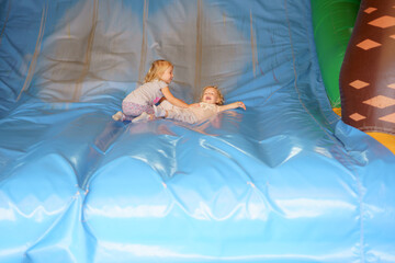 Children play joyfully on a large inflatable slide at a birthday party indoors during the afternoon