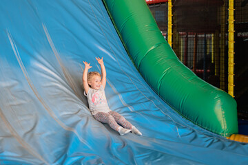 Child joyfully sliding down a colorful indoor playground slide during a fun-filled play session at a family entertainment center