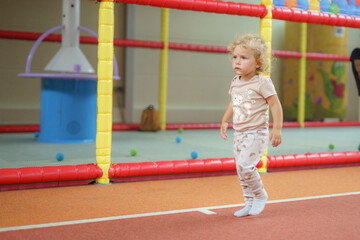 Young child enjoying active playtime in a colorful indoor play area with soft surfaces and safety barriers during the daytime