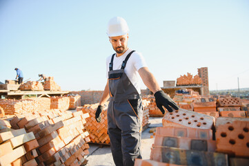 Installing brick wall. Construction worker in uniform and safety equipment have job on building