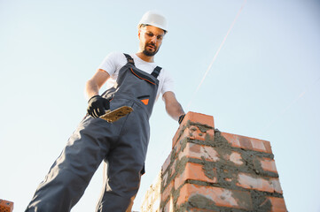 Installing brick wall. Construction worker in uniform and safety equipment have job on building