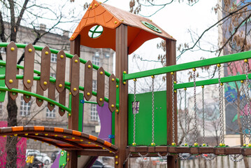 Vibrant children's playground equipment featuring climbing elements, bridges, and slides, offering fun and adventure within a dynamic urban area setting.