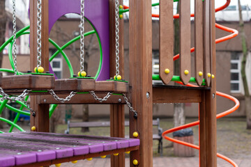 Colorful playground equipment made from wood and metal, featuring vibrant ropes and beams. The outdoor detailed architectural craftsmanship designed for children's playful activities.