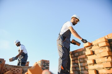 Professional construction workers build a brick house. Industrial theme of residential real estate...