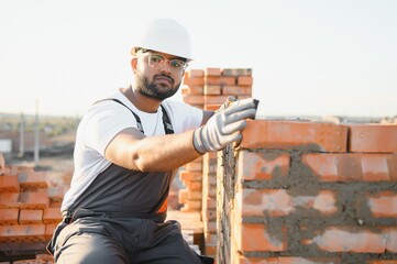 Indian Construction worker in uniform and safety equipment have job on building