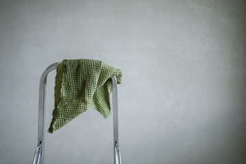 Soft green waffle towel draped over a metal ladder, creating a simple yet stylish scene against a...