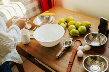 Young woman preparing a lemon cake, mixing ingredients on a rustic table with natural light,...