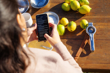 Girl ready to bake a lemon cake, looking at the recipe on her phone, with all ingredients arranged...