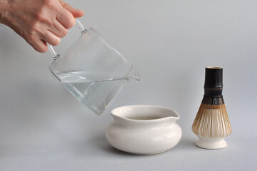 Japanese matcha tea preparation with traditional ceremony tools: white ceramic bowl chawan, glass...