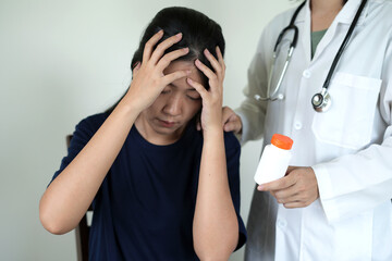 Doctor with stethoscope, standing in Hospital room is holding an medicine bottle to assess the...