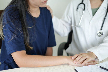 An asian psychiatrist or healthcare professional female doctor is gently holding patient hand comforting and encouragement, reassuring woman, only hands close up. Mental health care support concept.