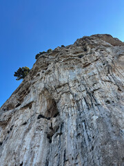 Detailed Rocky Cliff Face Against Clear Blue Sky from Below