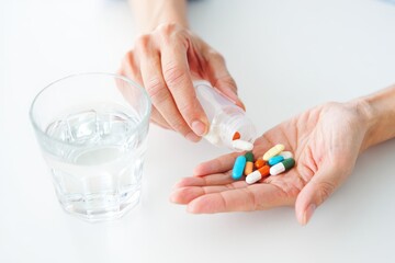 Person taking medication pouring pills into hand ready to take with glass of water