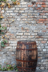 Weathered barrel beside a cracked brick wall, surrounded by creeping vines, with a blank, rustic backdrop for copy space