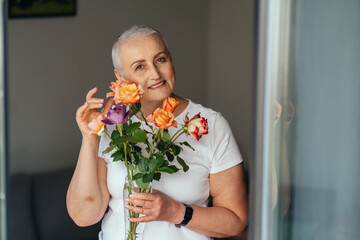 Joyful woman with bouquet smiling near window