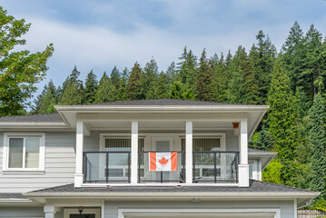 Top of grey stucco luxury house with shingle roof, green trees and nice windows in Spring in Vancouver, Canada, North America. Day time on May 2025.