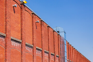 Low angle side view of old industrial building red brick wall against bright blue sky, Sherbrooke,...