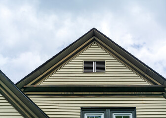 Obraz premium close-up view of a house gable roof with beige siding and vent in Brighton, Massachusetts, USA 