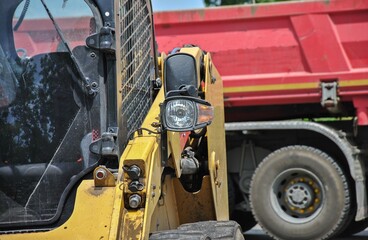 Headlight of a mini loader close up with a blurry truck in the background. selective focus of construction equipment