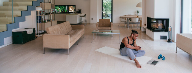 Training At Home. Sporty man doing the training while watching an online tutorial on a laptop,...