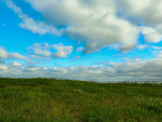 Landscape, on the horizon a green hill meets a sky covered with clouds