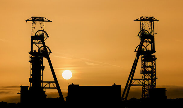 Coal Mine headstocks at sunset. Mining history in the UK. large silhouetted winding wheels with the sunset behind. Yorkshire, Nottinghamshire and welsh coal mines