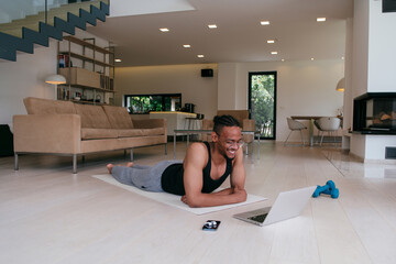 Training At Home. Sporty african american man doing the training while watching an online tutorial...