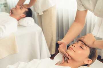 Obraz premium Caucasian couple enjoying relaxing anti-stress head massage and pampering facial beauty skin recreation leisure in dayspa modern light ambient at luxury resort or hotel spa salon. Quiescent