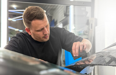 A car wrapping specialist applies a matte polyurethane film to the car. Selective focus. PPF protective film against chips and scratches. Car wrapping. Wrapping protective film on the car. 