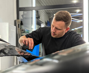 A car wrapping specialist applies a matte polyurethane film to the car. Selective focus. PPF protective film against chips and scratches. Car wrapping. Wrapping protective film on the car. 