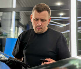 A car wrapping specialist applies a matte polyurethane film to the car. Selective focus. PPF protective film against chips and scratches. Car wrapping. Wrapping protective film on the car. 
