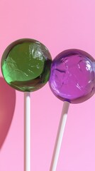 Colorful lollipops in green and purple displayed against a bright pink background