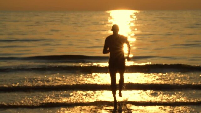 a man is running into the sea at sunset
