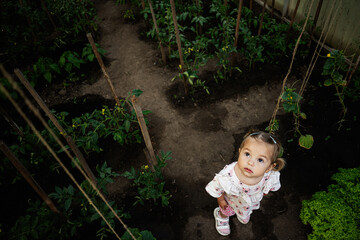 Curious child exploring a lush garden environment surrounded by plants