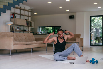 Training At Home. Sporty African American man doing the training while watching an online tutorial...