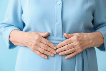 Obraz premium close-up of elderly hands expressing serenity in light blue clothing, the light blue shirt suggests gentleness, care, and peacefulness. old woman's hand, 60 years old, senior nurse's hand