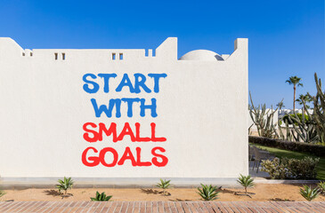 Start with small goals symbol. Concept words phrase Start with small goals on beautiful white wall....