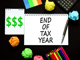 End of tax year symbol. Concept words phrase End of tax year on beautiful white note. Colored paper. Calculator. Beautiful black background. Business End of tax year concept. Copy space.