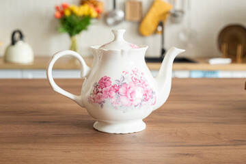 Beautiful white teapot with flowers for tea in the kitchen