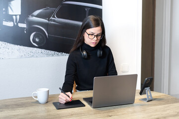 Designer woman working on graphic tablet with laptop in modern space.