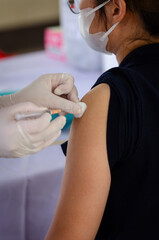 Concept of vaccination against epidemic, woman wearing medical face mask is getting vaccinated against epidemic at hospital medical center