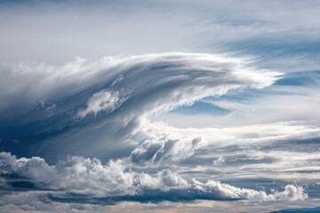 Obraz premium Dynamic clouds combine to create a wave-like structure under a clear sky, showcasing nature's beauty and artistry