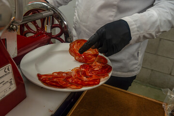 Chef preparing sliced cured meat with slicing machine at event