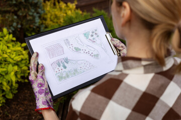 landscape design. woman gardener looking at home backyard garden plan