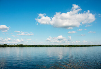 Panoramic view of the Dnieper River bank. Reflection of sky with clouds on the water surface.