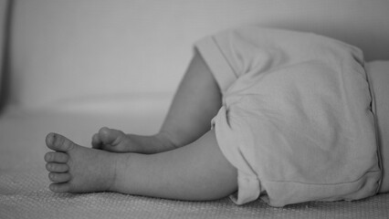 Monochrome image of baby legs and feet resting on a blanket. Soft and peaceful atmosphere capturing...